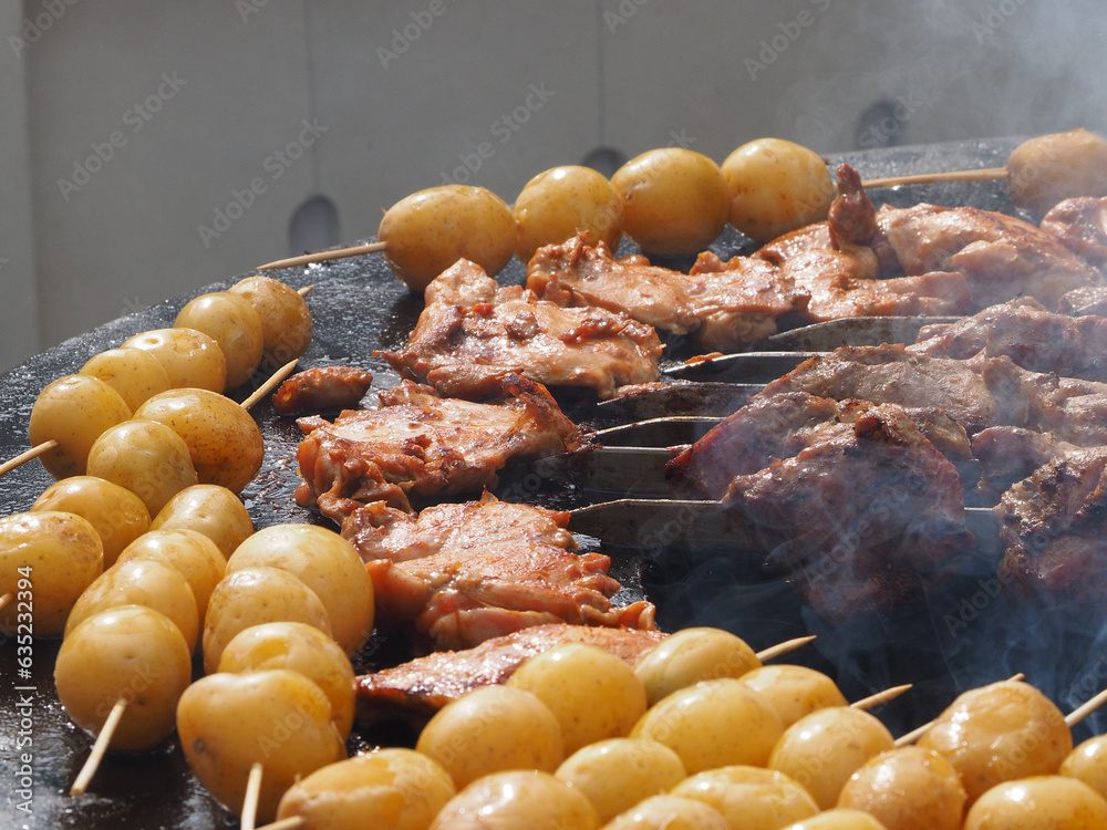 Potatoes, delicious fried tubers, with a golden crust, grilled, on the background of a brazier and fire. Fried potatoes, on skewers, close-up.