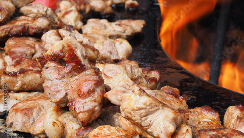 Obraz na płótnie Meat, delicious fried pieces, with a golden crust, cooked on the grill, against the background of a brazier and fire. Pieces of fried meat, close-up. w salonie
