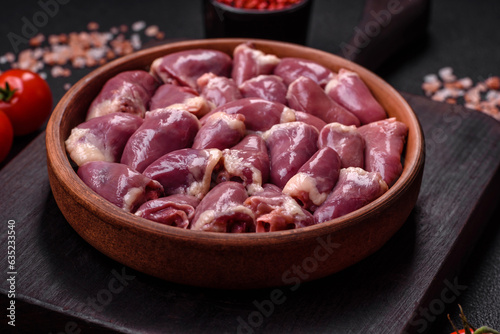 Fresh raw chicken or turkey hearts in a ceramic plate with salt, spices and herbs