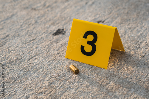 One yellow crime scene evidence marker on the street after a gun shooting brass bullet shell casing 9mm handgun pistol