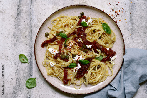 Pasta bavette with dried tomatoes, kapers and ricotta  . Top view with copy space. photo