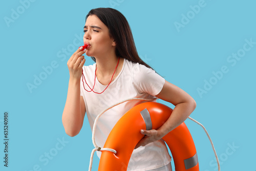 Foto Female lifeguard with ring buoy whistling on blue background