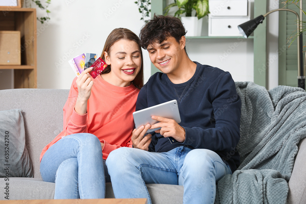 Young couple with tablet computer and gift cards shopping online at home Young couple with tablet computer and gift cards shopping online at home