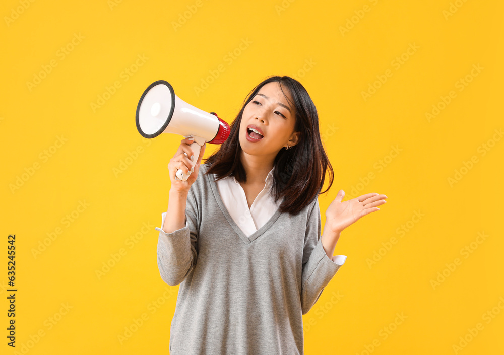 Beautiful Asian woman shouting into megaphone on yellow background. Dialogue concept Beautiful Asian woman shouting into megaphone on yellow background. Dialogue concept