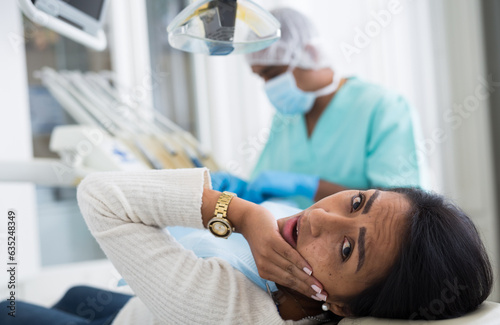Tableau sur toile Adult Latina suffering from toothache lying on dental chair waiting for qualifie
