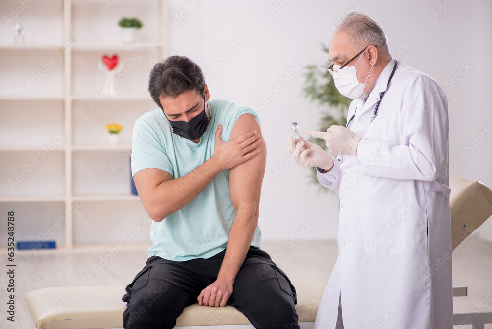 Obraz premium Young male patient visiting old male doctor in vaccination conce