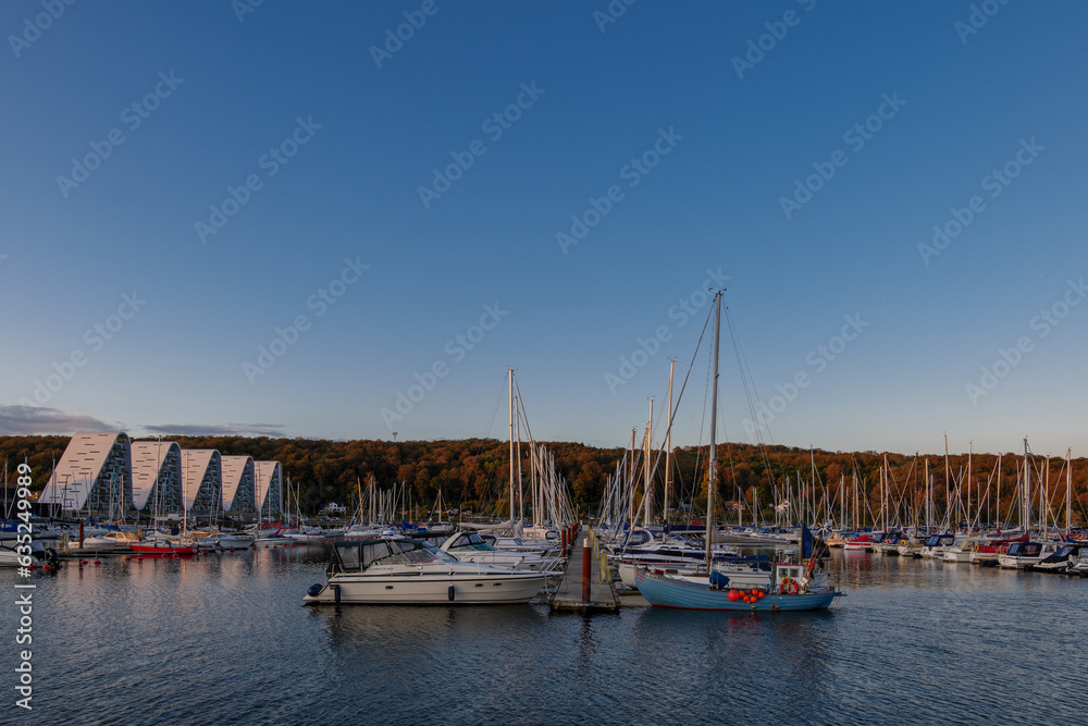Outdoor exterior view at Vejle Havn Mole, row of yachts pier and the wave apartment during twilight sky in Vejle, Denmark.