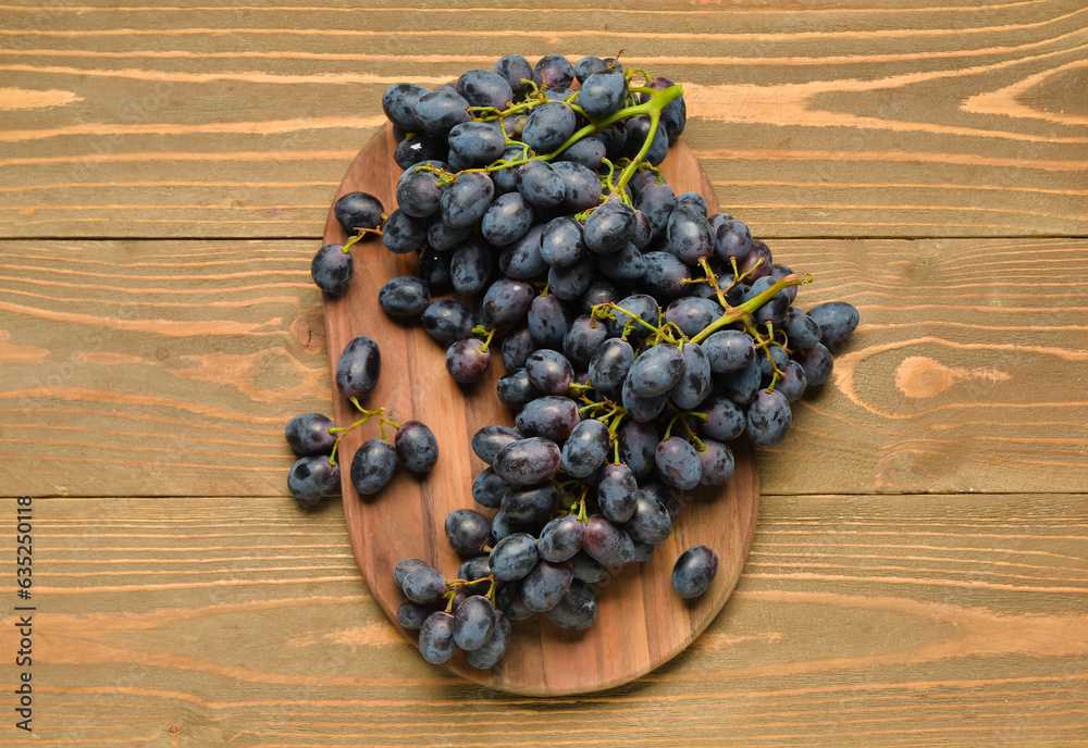 Board with sweet black grapes on wooden background Board with sweet black grapes on wooden background