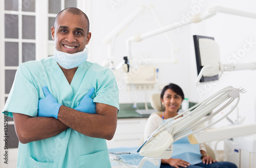 Portrait of positive dentist in dental office on the background of patient