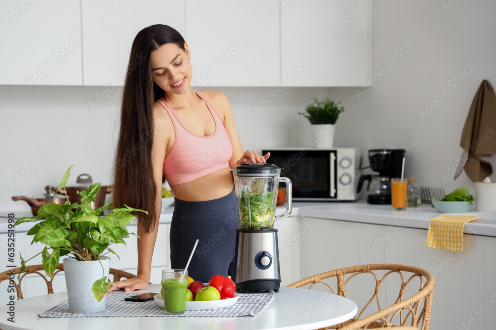 Sporty young woman making healthy smoothie with blender in kitchen Sporty young woman making healthy smoothie with blender in kitchen