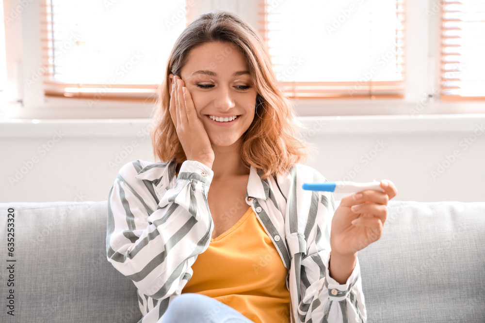 Happy young woman with pregnancy test at home