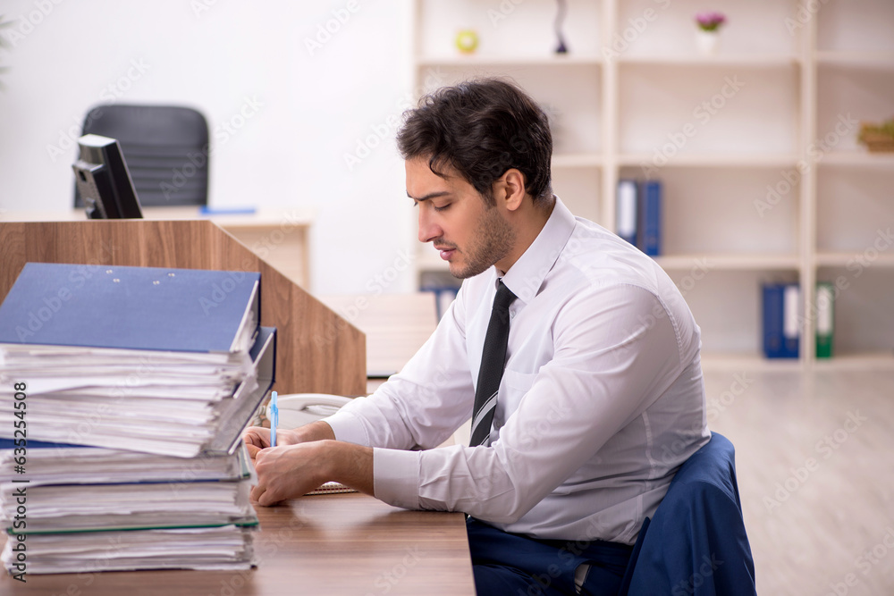 Young male employee and too much work in the office Young male employee and too much work in the office