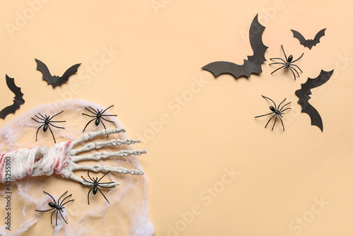Skeleton hand, web, spiders and paper bats for Halloween celebration on beige background © Pixel-Shot