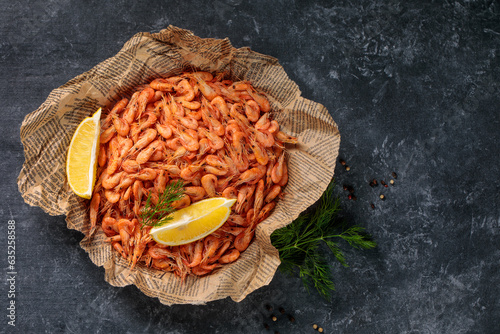 Small shrimps cooked in a bowl with lemon, garlic on a gray background