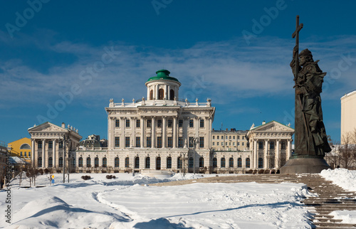 View of elegant neoclassical building of Pashkov House on Vagankovsky Hill in Moscow with monument to Vladimir Great in foreground on sunny winter day photo