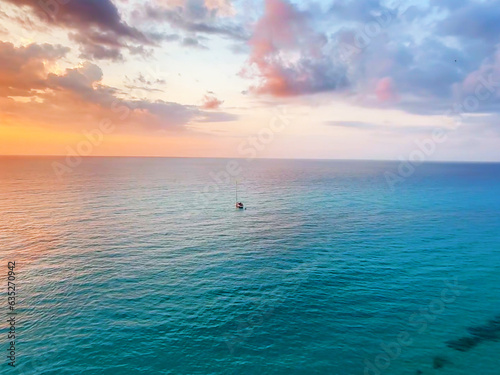 Italian Sunset Splendor: Colorful Skies Reflecting on Turquoise Waters with a Little Boat Floating in the Azure Sea