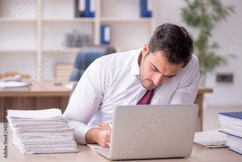 Young male employee and too much work at workplace