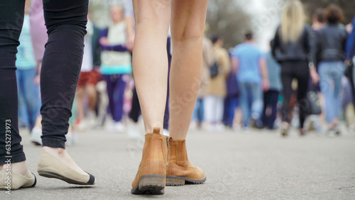 Abstract blurred background of crowd of people on city street, close-up of girls legs, selective focus