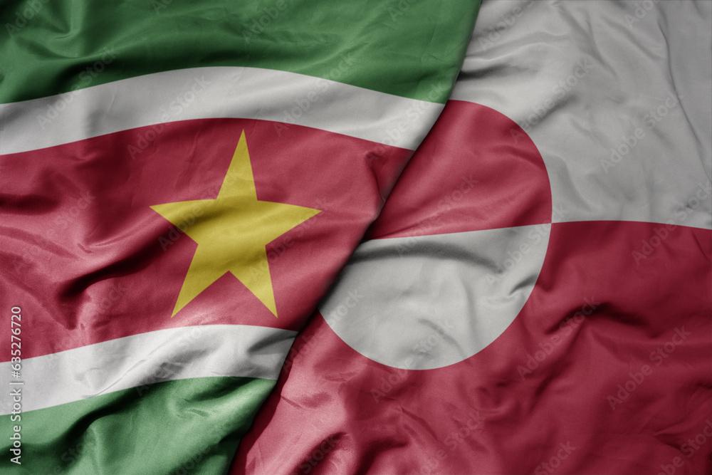 big waving realistic national colorful flag of suriname and national flag of greenland .