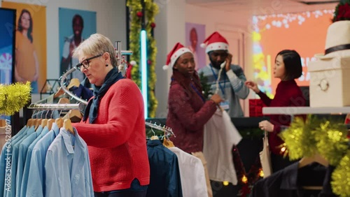 Wallpaper Mural Senior woman browsing through blazer racks in clothing shop men section, looking for perfect Christmas gift for son during winter holiday season. Client in fashion boutique checking clothes Torontodigital.ca