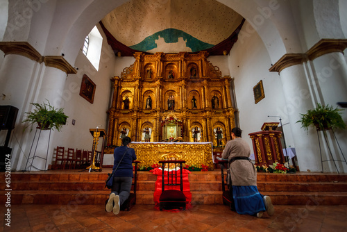 Fotografie Two women pray in front of the altar of the main parish of Villa de Leyva, Colom