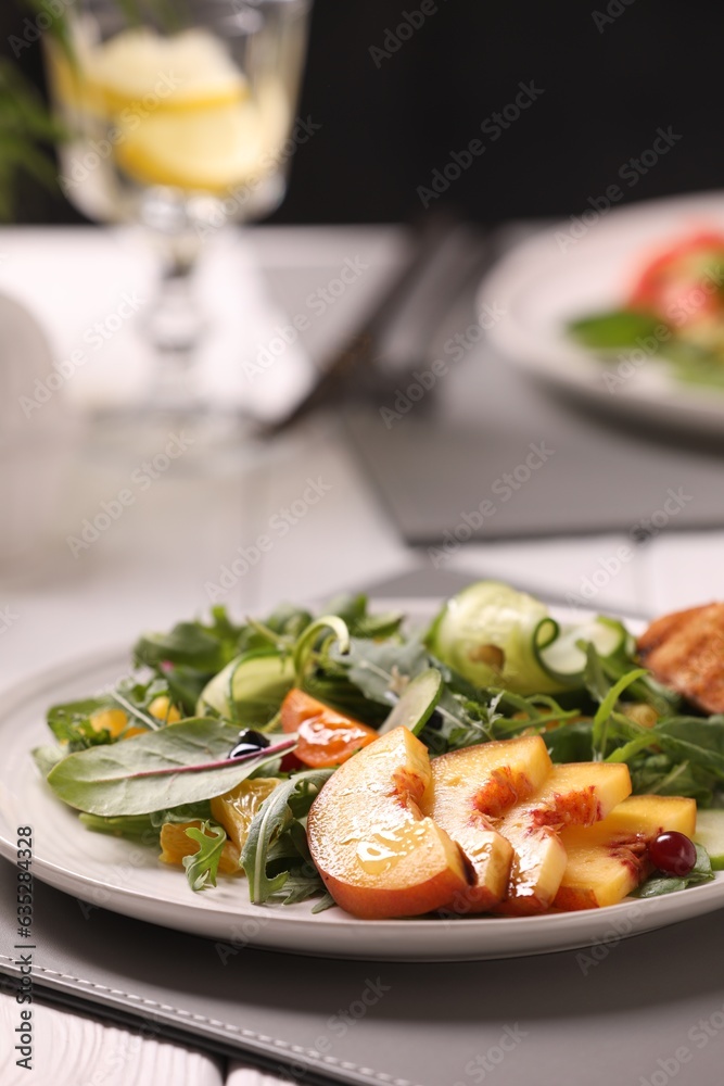 Delicious salad with peach slices on table