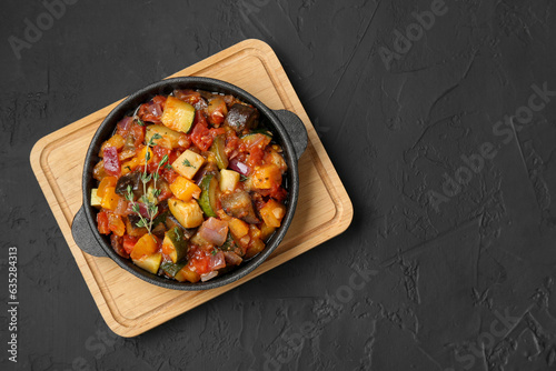 Dish with tasty ratatouille on black table, top view. Space for text