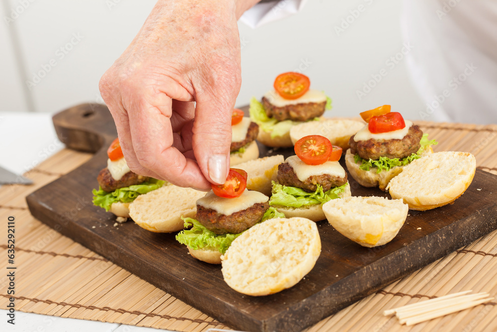 Step by step preparation of mini burgers. Homemade mini burgers for children or appetizers. Small hamburgers. Assembling burgers Step by step preparation of mini burgers. Homemade mini burgers for children or appetizers. Small hamburgers. Assembling burgers