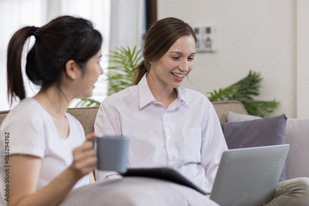 Two Happy asian Ladies Using Laptop Computer Working And Learning Online Together Or Making Video Call Sitting At on sofa in home . E-Learning. Females Entrepreneurship Career Concept. Two Happy asian Ladies Using Laptop Computer Working And Learning Online Together Or Making Video Call Sitting At on sofa in home . E-Learning. Females Entrepreneurship Career Concept.
