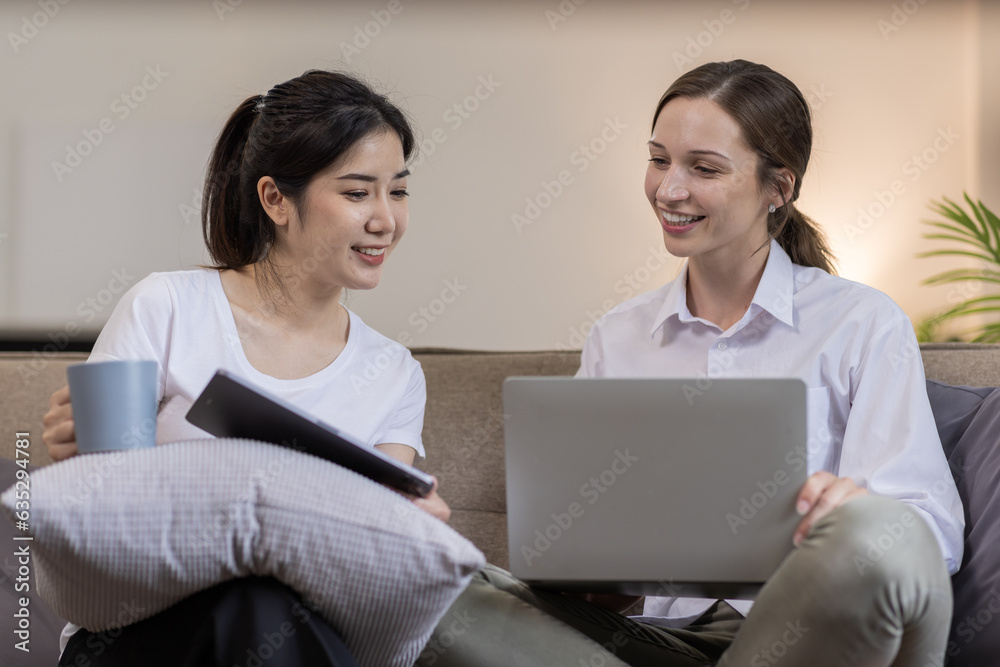 Two Happy asian Ladies Using Laptop Computer Working And Learning Online Together Or Making Video Call Sitting At on sofa in home . E-Learning. Females Entrepreneurship Career Concept. Two Happy asian Ladies Using Laptop Computer Working And Learning Online Together Or Making Video Call Sitting At on sofa in home . E-Learning. Females Entrepreneurship Career Concept.