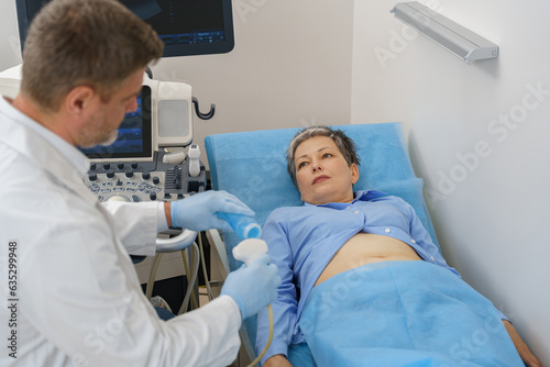 Male sonographer doing abdominal ultrasound scanning for patient in medical clinic