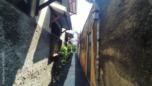 View through a narrow alley in a densely populated settlement in Jakarta. Suburban area.
