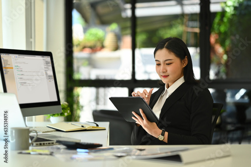 Rear view programer asian woman working on digital tablet.