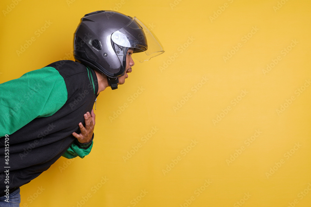 Shocking Asian online taxi driver motorbike man showing from the side isolated over yellow background with copy space