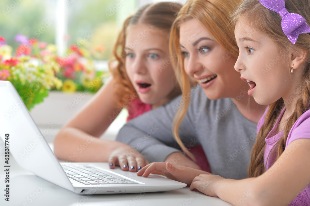 Mother and girls sitting at table and using laptop Mother and girls sitting at table and using laptop