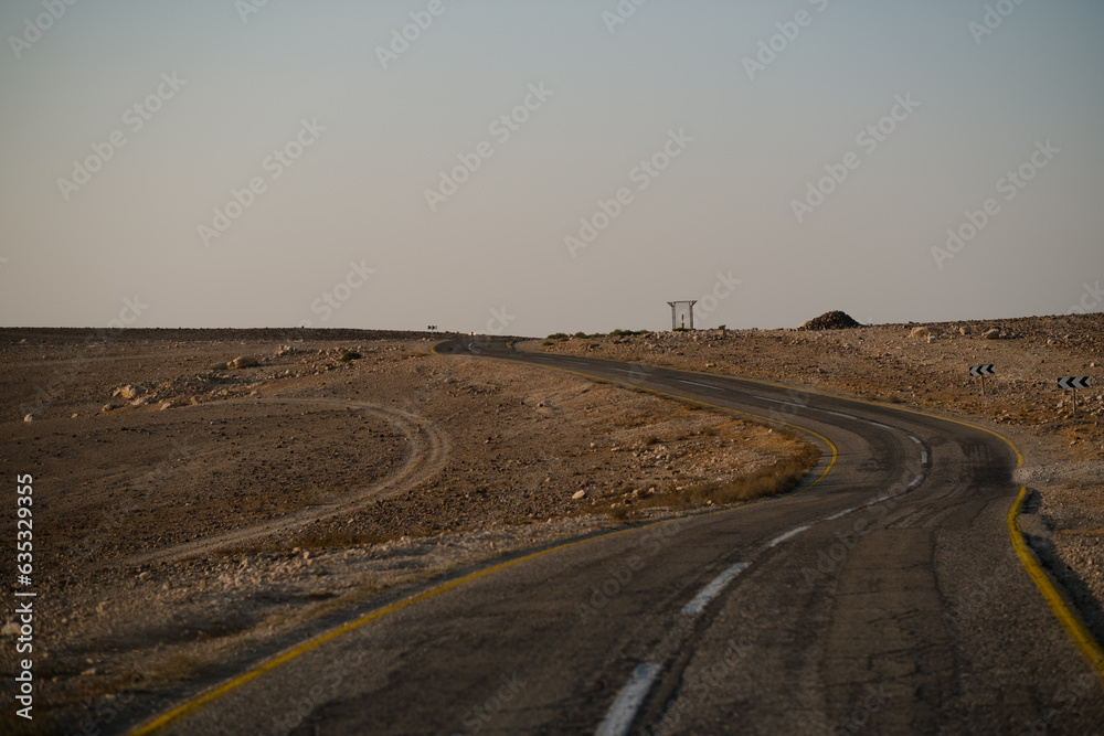 In the Negev Desert, a two-line highway curves its way through the wilderness and disappears over the top of a hill. The sky is hazy, after a windy storm swept across southern Israel.