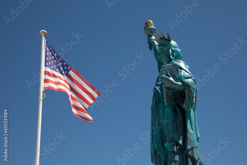 American flag National states flag on wind mat us with copper Statue of Liberty sculpture on Liberty Island in New York Harbor © OceanProd
