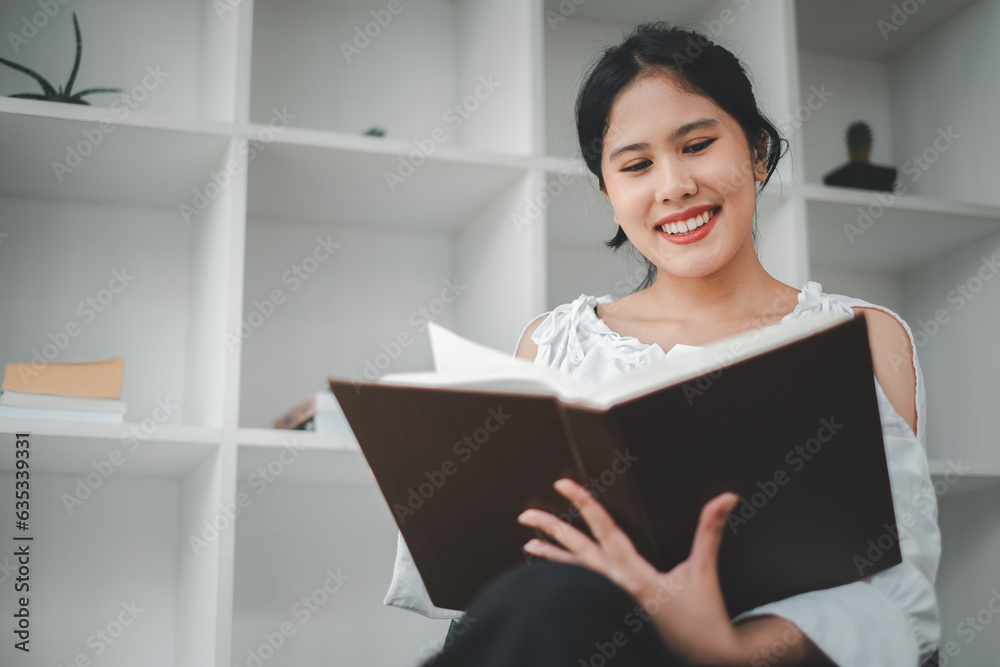 Asian woman sitting in cozy armchair with open book indoors. Beautiful young lady reading exciting story, enjoying lazy morning, Asian woman sitting in cozy armchair with open book indoors. Beautiful young lady reading exciting story, enjoying lazy morning,