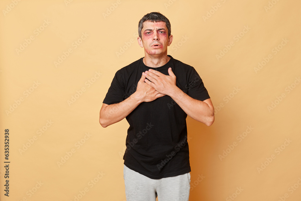 Φωτογραφία Unhealthy unhappy man in black T-shirt with bruises and abrasions on his face isolated over beige background feeling strong pain chest after car accident