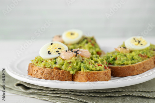 Slices of bread with tasty guacamole, eggs and shrimp on table, closeup