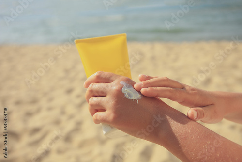 Child applying sunscreen near sea, closeup. Space for text. Sun protection care