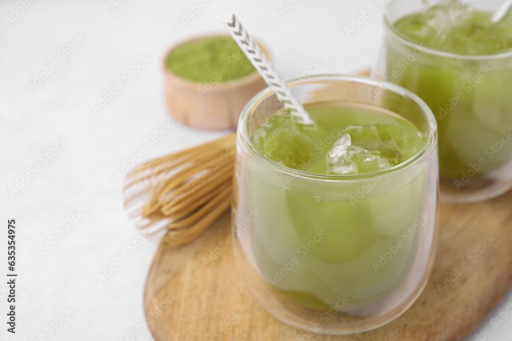 Delicious iced green matcha tea and bamboo whisk on white table, closeup. Space for text Delicious iced green matcha tea and bamboo whisk on white table, closeup. Space for text