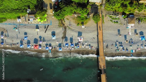 Aerial view of beach and umbrellas. Stay. Beach and blue water. Drone view of beach and the azure sea in Georgia Chakvi View of Black Sea coast. Beach coastline - summer day, people swim, sunbathe photo