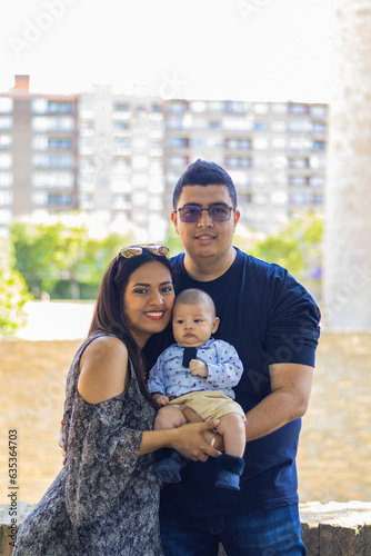 Couple with their newborn baby in their arms in a park