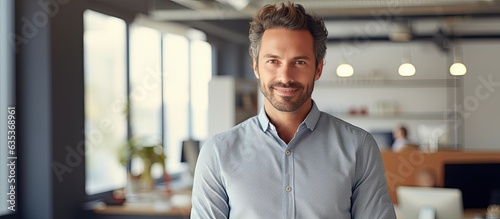 Confident young businessman posing in office looking at camera and smiling