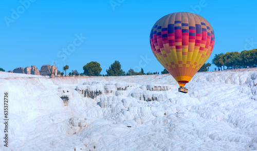 Hot air balloon flying over spectacular Pamukkale - Natural travertine pools and terraces in Pamukkale. Cotton castle in southwestern Turkey,
