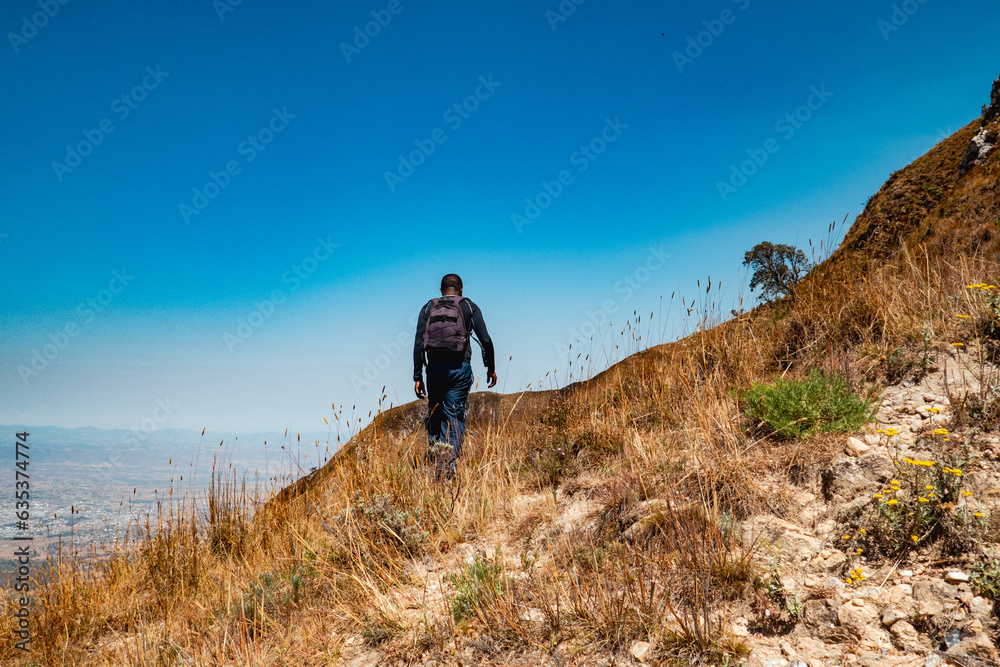 A hiker against the background of Mbeya Paek in Mbeya Mountain Range in Tanzania