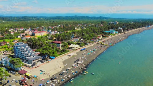 Aerial view of beach and umbrellas. Stay. Beach and blue water. Drone view of beach and the azure sea in Georgia Chakvi View of Black Sea coast. Beach coastline - summer day, people swim, sunbathe photo