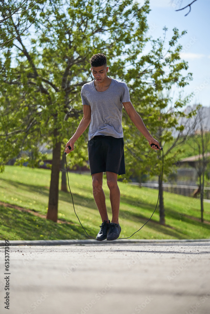Young man with skipping rope in summer park
