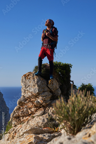 Male hiker with backpack standing on rocky cliff